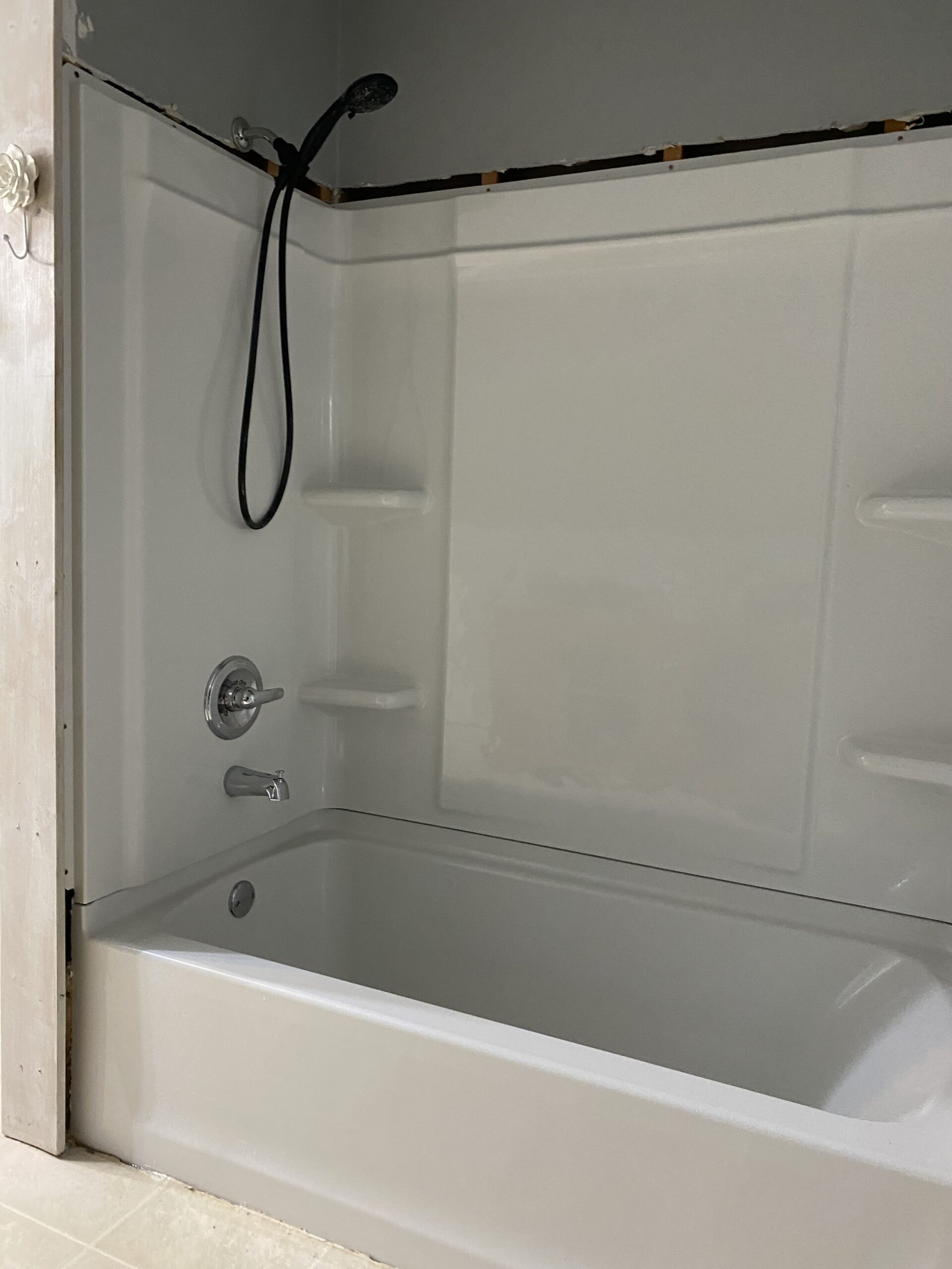 A white bathtub with shower fixtures and built-in wall shelves.